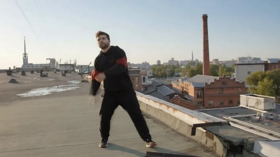 The same clip after the edit, the same rooftop and dancer under a brighter sky with warmer light