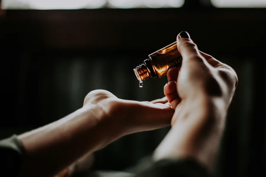 A photograph of hands with massage oil being poured from a bottle