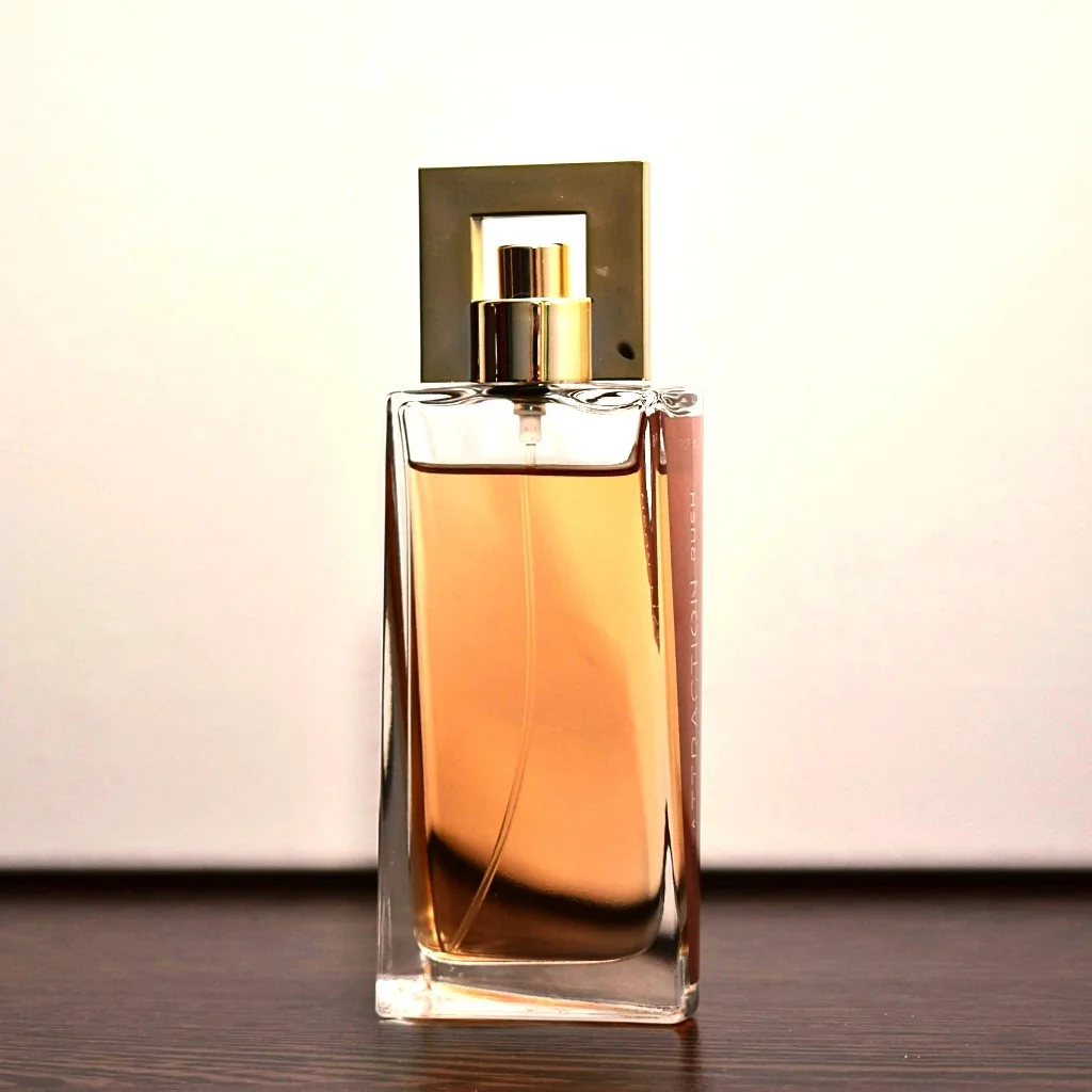 The same perfume bottle photo with warm light falling across the glass and a cream tint lifting the background