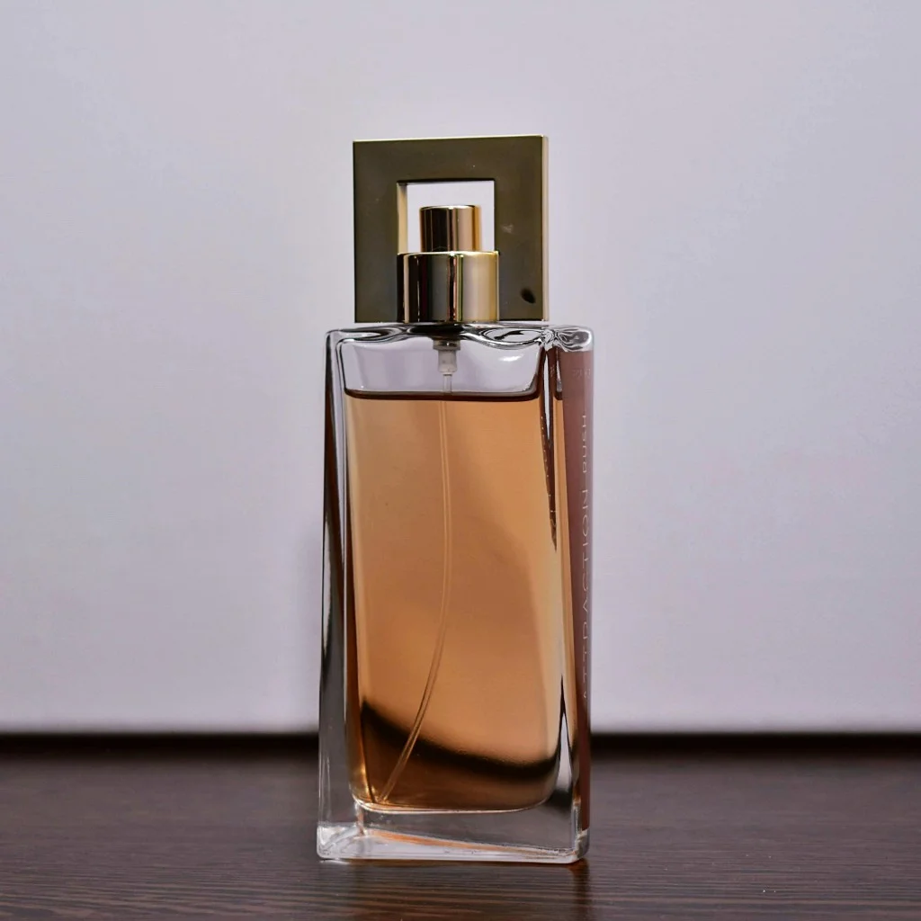 Perfume bottle photographed on a dark wooden table against a plain wall, evenly lit and flat