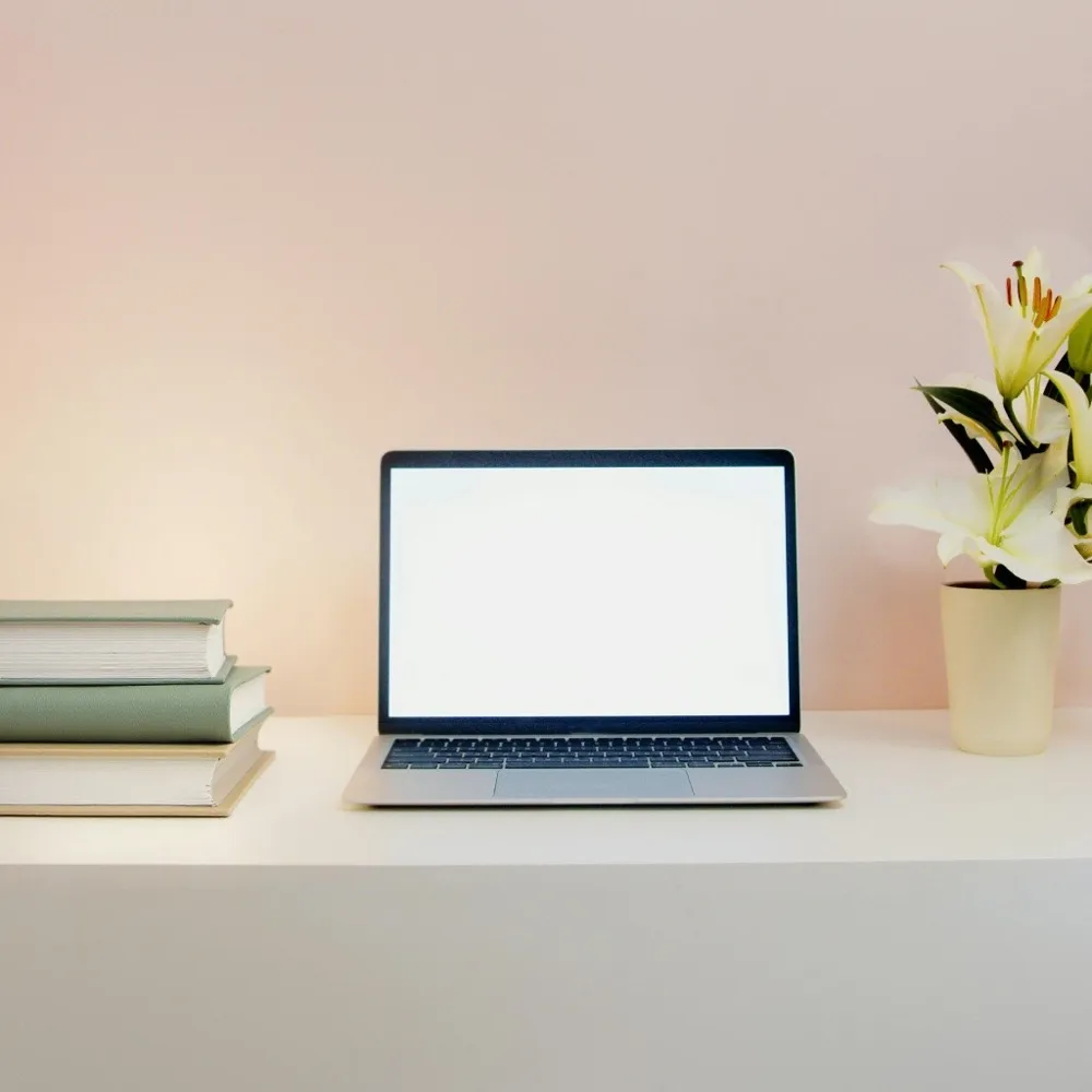 The same desk scene with the lamp replaced by a stack of cream and sage hardcover books