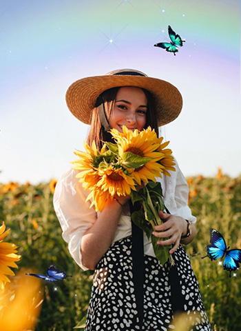 Happy woman holding a sunflower, standing among a field of sunflowers, basking in the sunlight