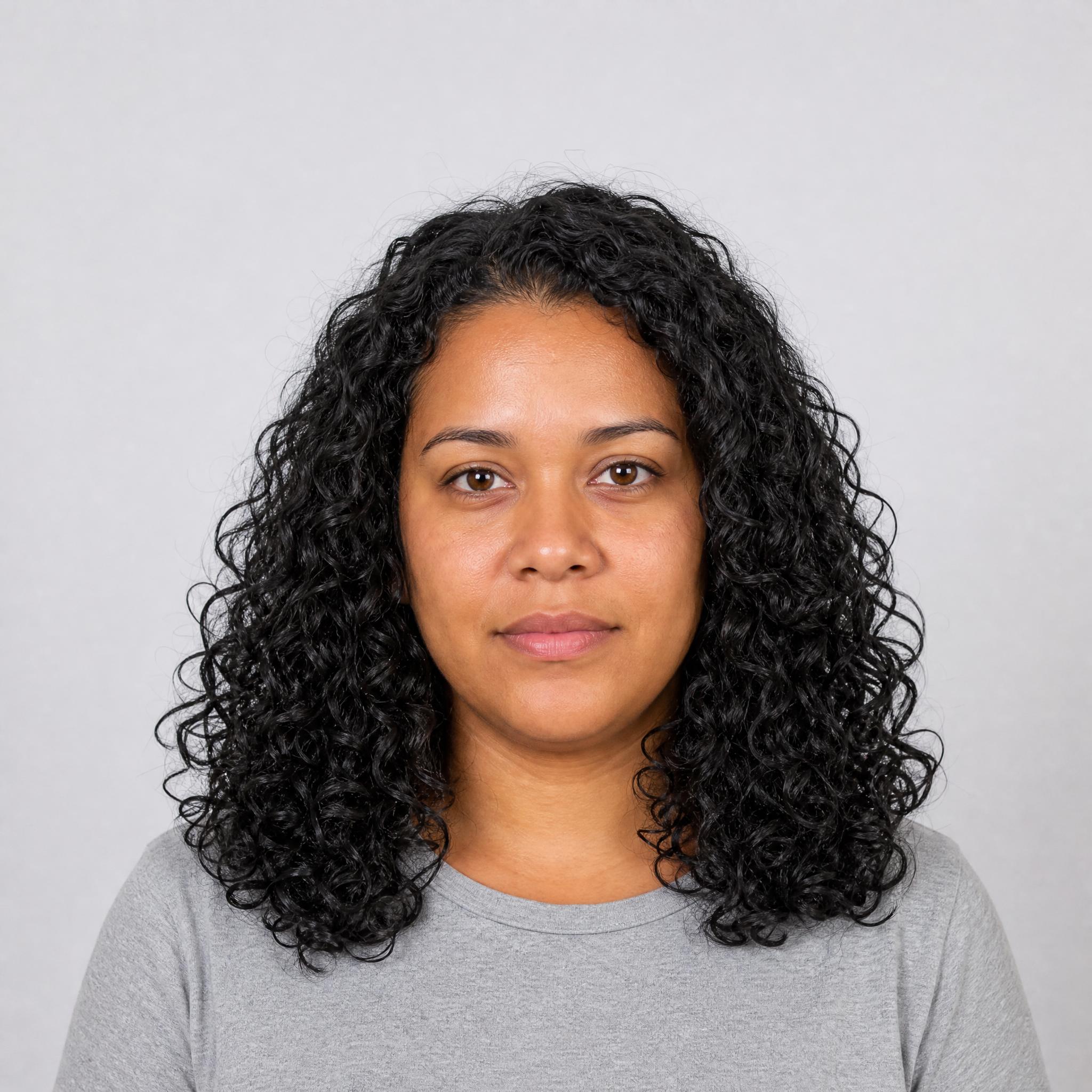 Retrato de partida de mujer con cabello negro rizado hasta los hombros sobre fondo gris claro