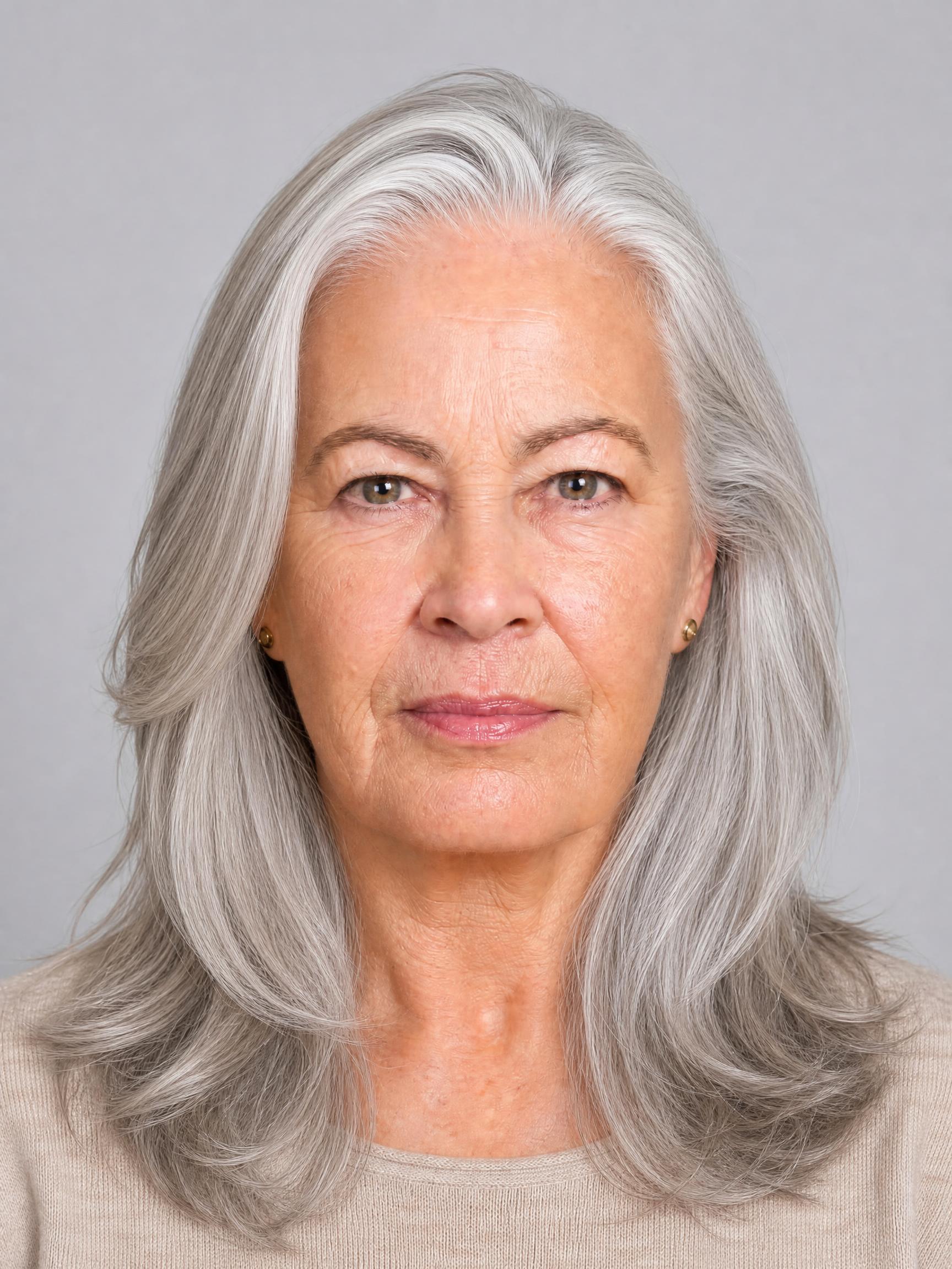 Mujer de unos 60 años con melena larga y capas sutiles en cabello plateado, puntas hidratadas y movimiento natural