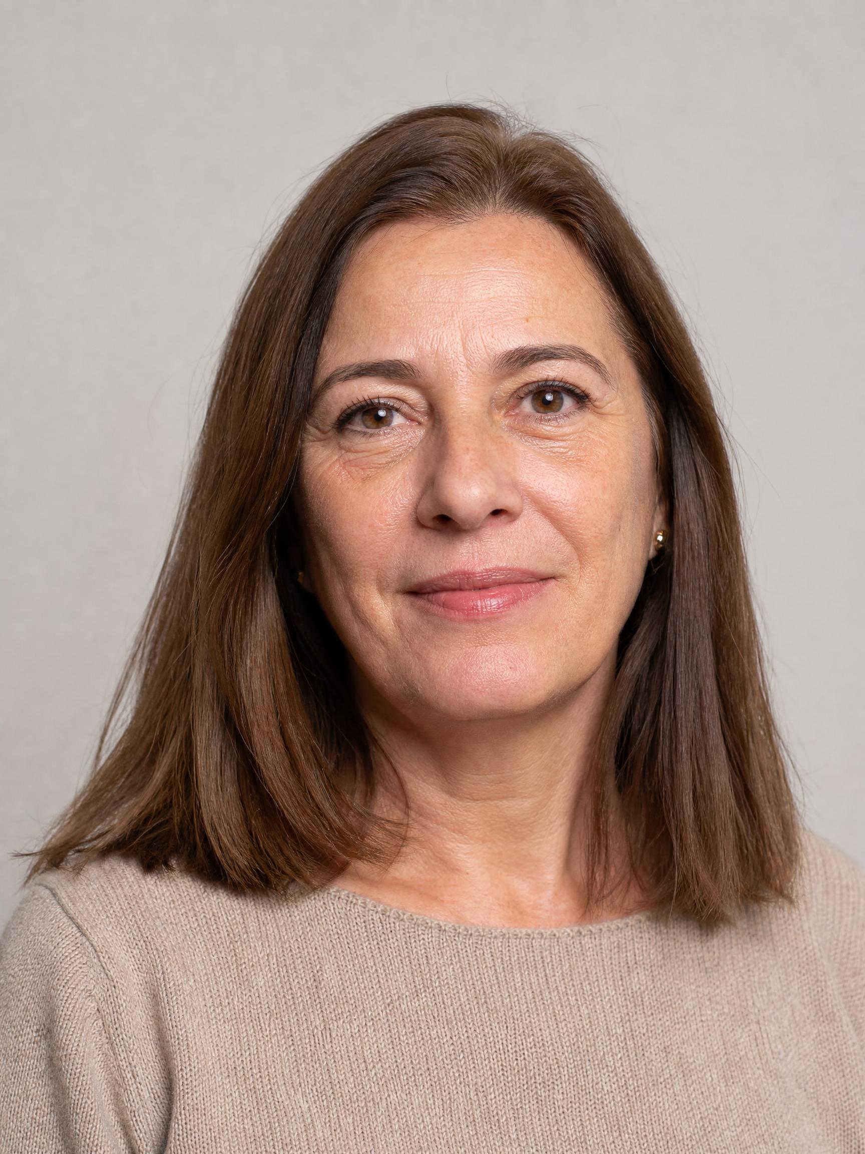 Antes: retrato frontal de una mujer de unos 55 años con melena lisa castaña a los hombros sobre fondo gris liso