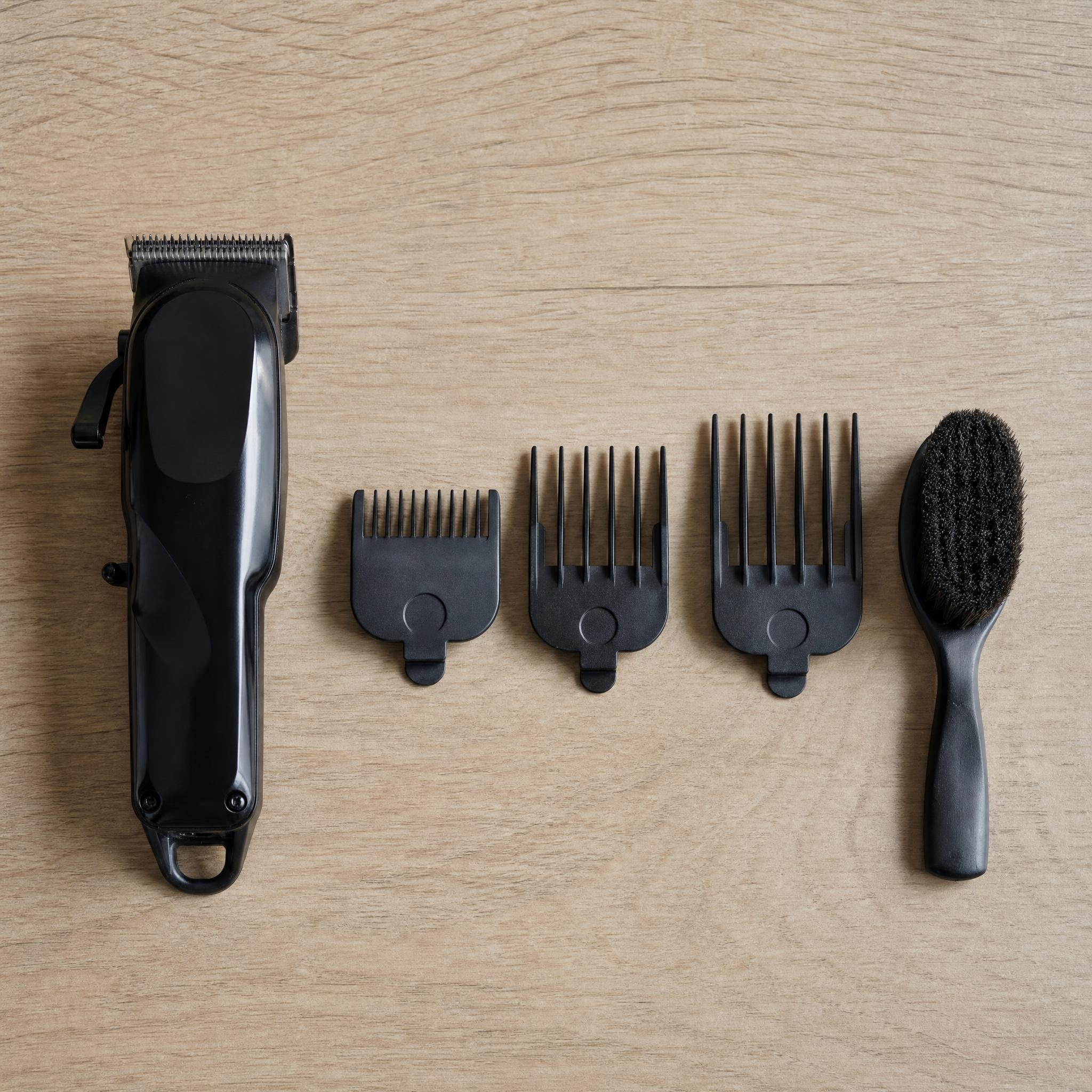 Maquinilla de barbero junto a tres peines guía de distinto número sobre una superficie de madera