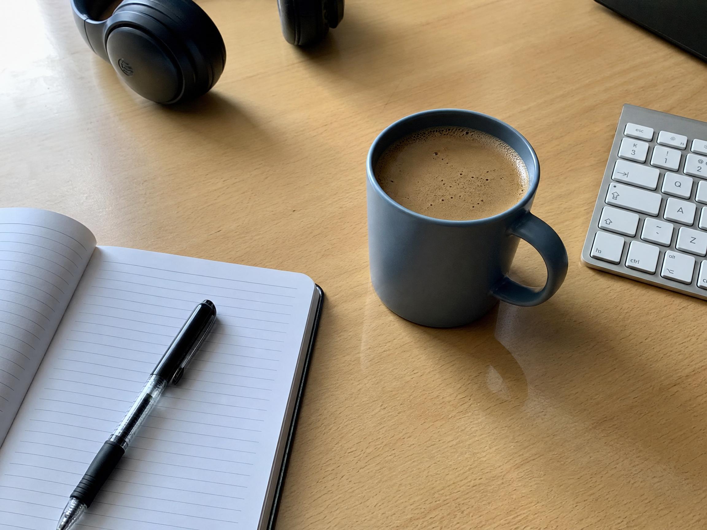 Antes: escritorio con una taza de café azul junto al teclado y un cuaderno abierto