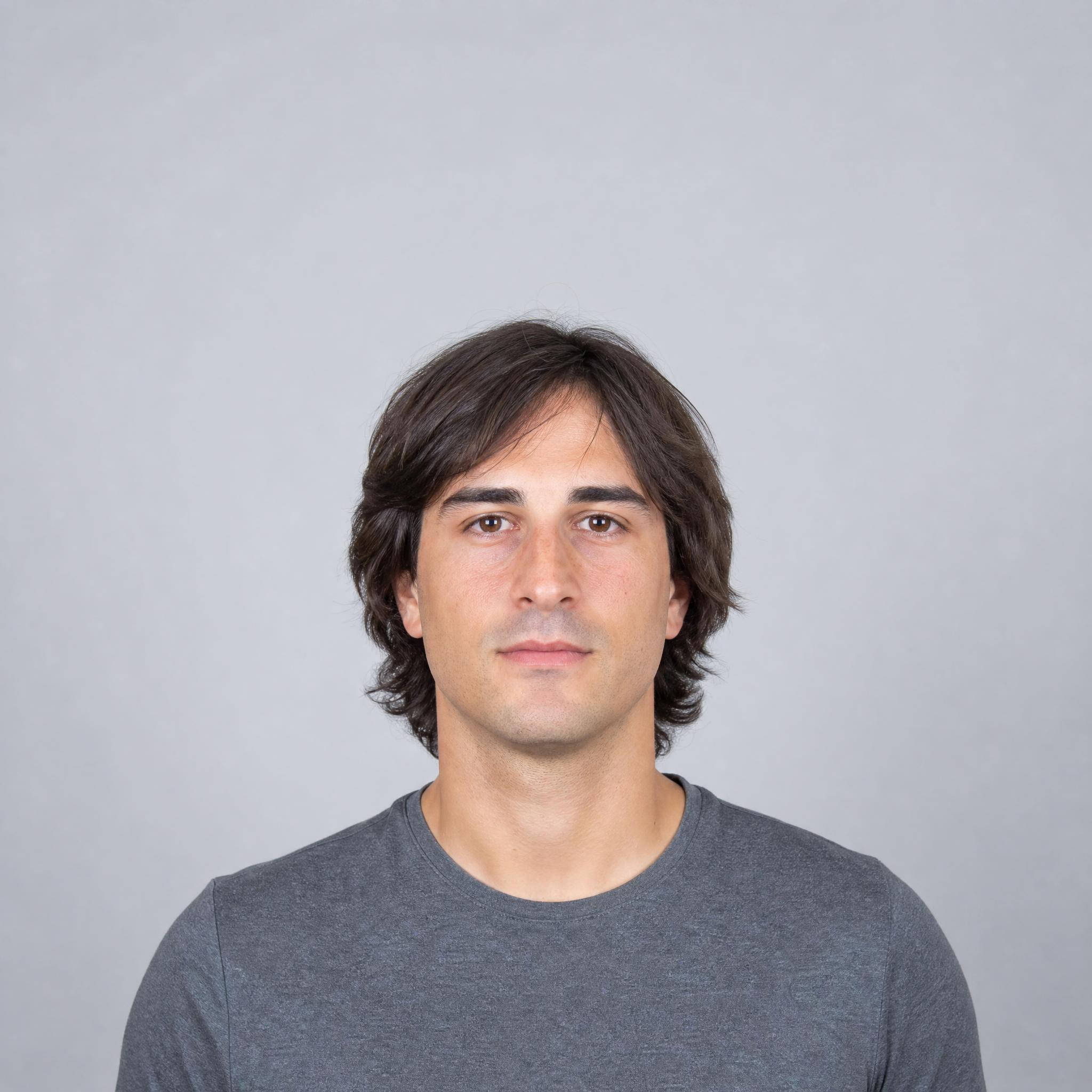 Retrato de partida masculino con cabello castaño de longitud media sobre fondo gris claro