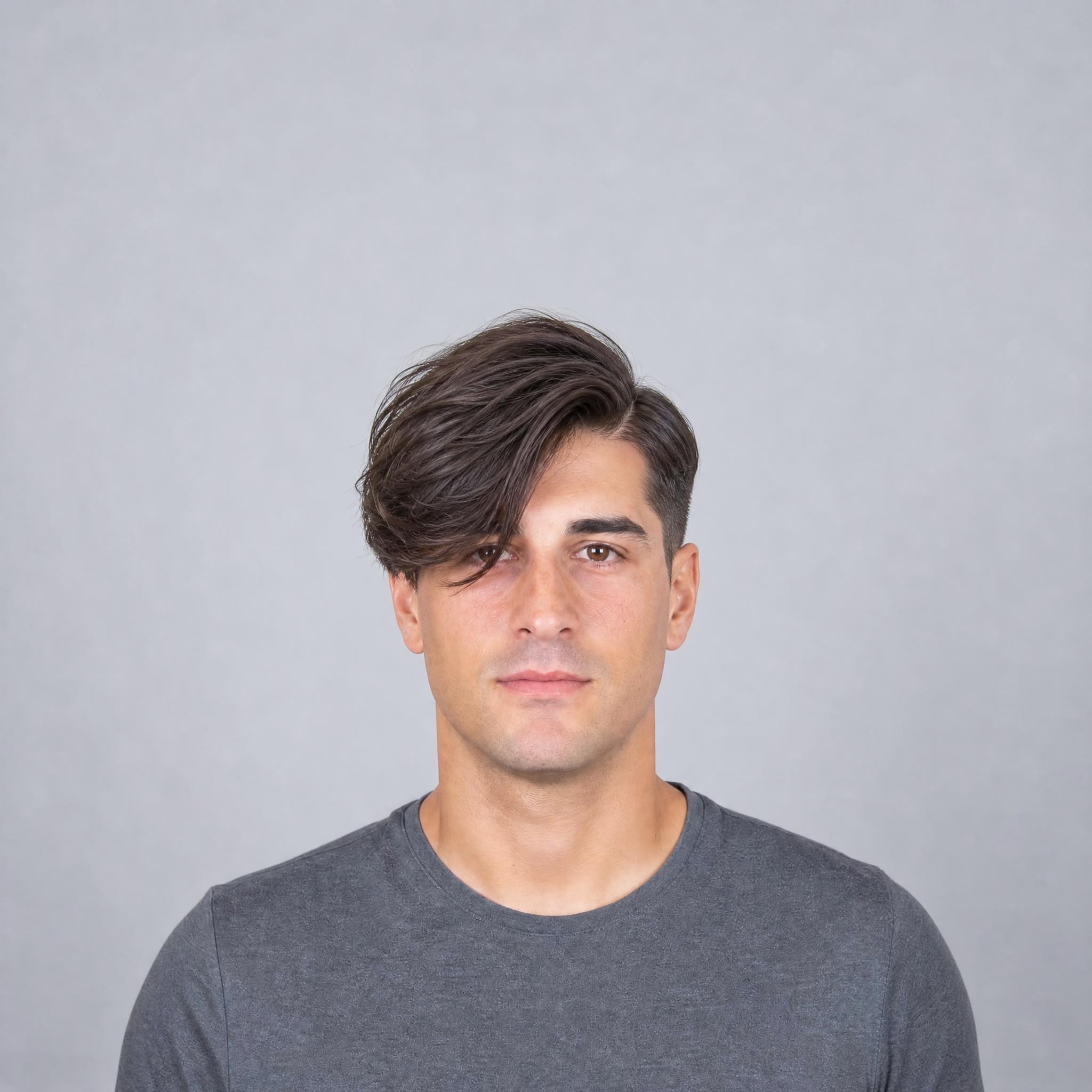 Flequillo new wave largo y asimétrico con volumen fijado cayendo sobre un lado del rostro en el retrato de partida masculino