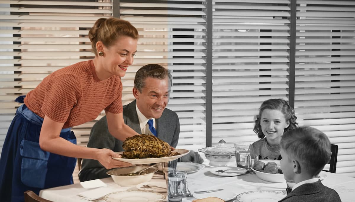 Ein Split-Screen-Vergleich eines alten Familienfotos beim Abendessen; die rechte Seite ist im originalen Schwarz-Weiß, die linke Seite wurde mittels KI realistisch koloriert.