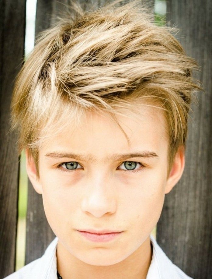Ein blonder Junge mit einem lässigen Messy-Look, bei dem das mittellange, gestufte Haar wild und strukturiert nach oben gestylt ist.