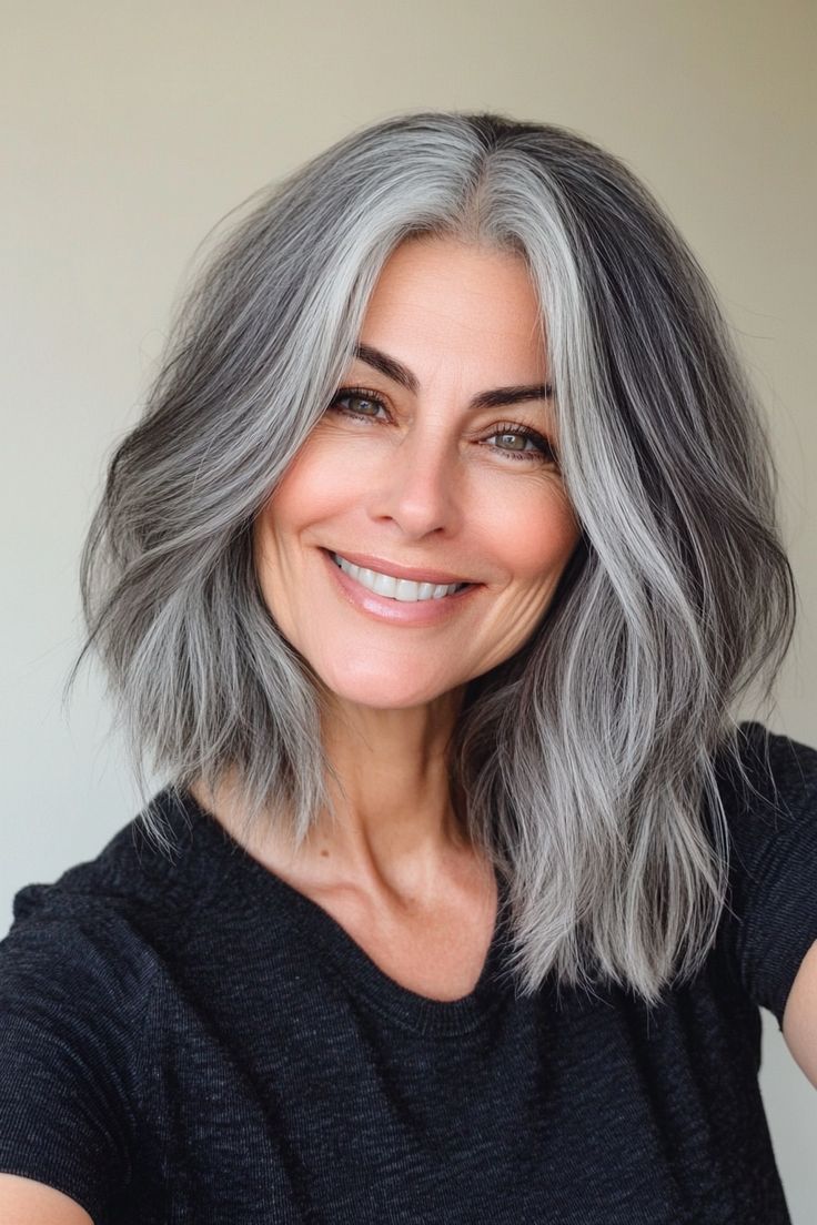 Femme avec coupe lob texturée, cheveux gris ondulés au-dessus des épaules, bureau moderne avec grandes fenêtres, portrait professionnel réaliste