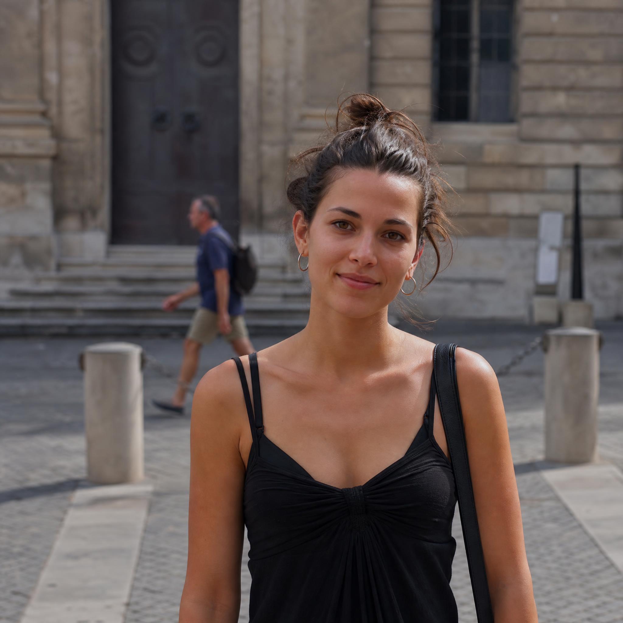 Foto original de una mujer en una plaza con un desconocido al fondo, antes de aplicar el prompt de eliminación de persona en Grok