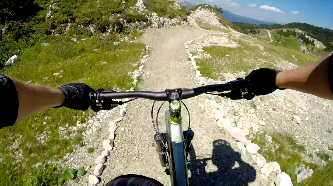 A handlebar view of a gravel trail where the wide lens curves the handlebar and the edges of the frame