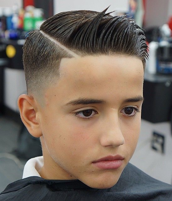 Ein trendiger Undercut bei einem Jungen mit sehr kurz rasierten Seiten, einem präzise einrasierten Scheitel und zur Seite gestyltem Deckhaar.